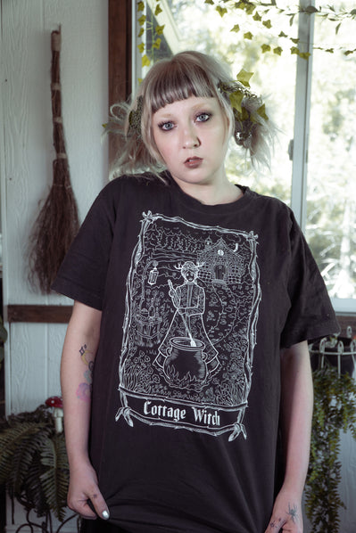 Model wearing the Cottage Witch Tee by The Pretty Cult, black cotton witch graphic t-shirt